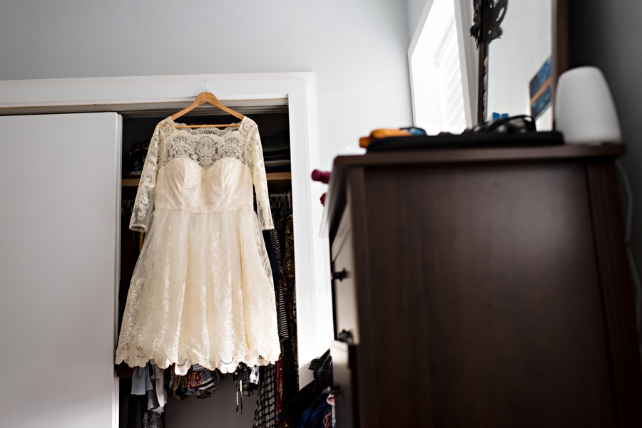 A beautiful short lacy wedding dress hangs in the bedroom in the bride's home in south Philadelphia